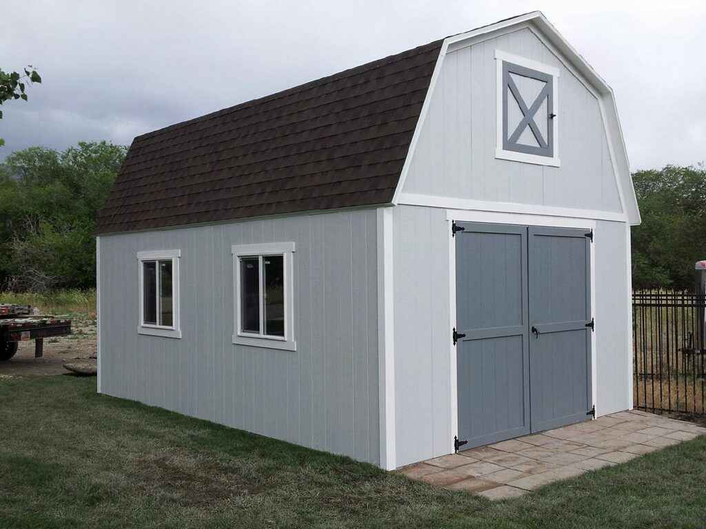 A stylish gray farm-style shed with a gambrel roof, double doors, and classic windows.